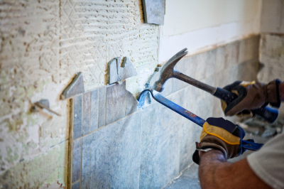 Eine Wand wird saniert, Fliesen werden mit Hammer abgeschlagen